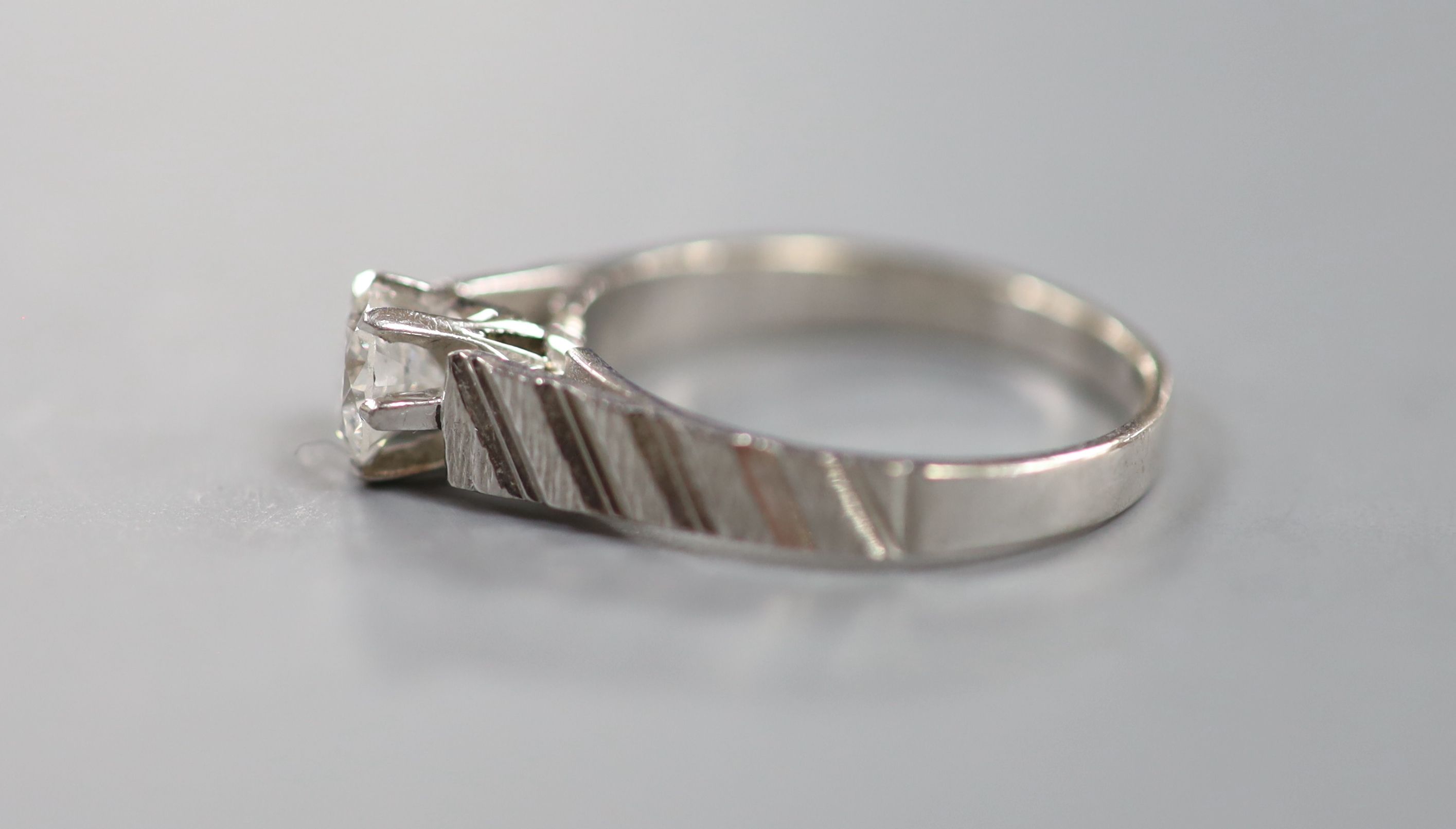 A modern 18ct white metal and solitaire diamond ring, with engraved shoulders